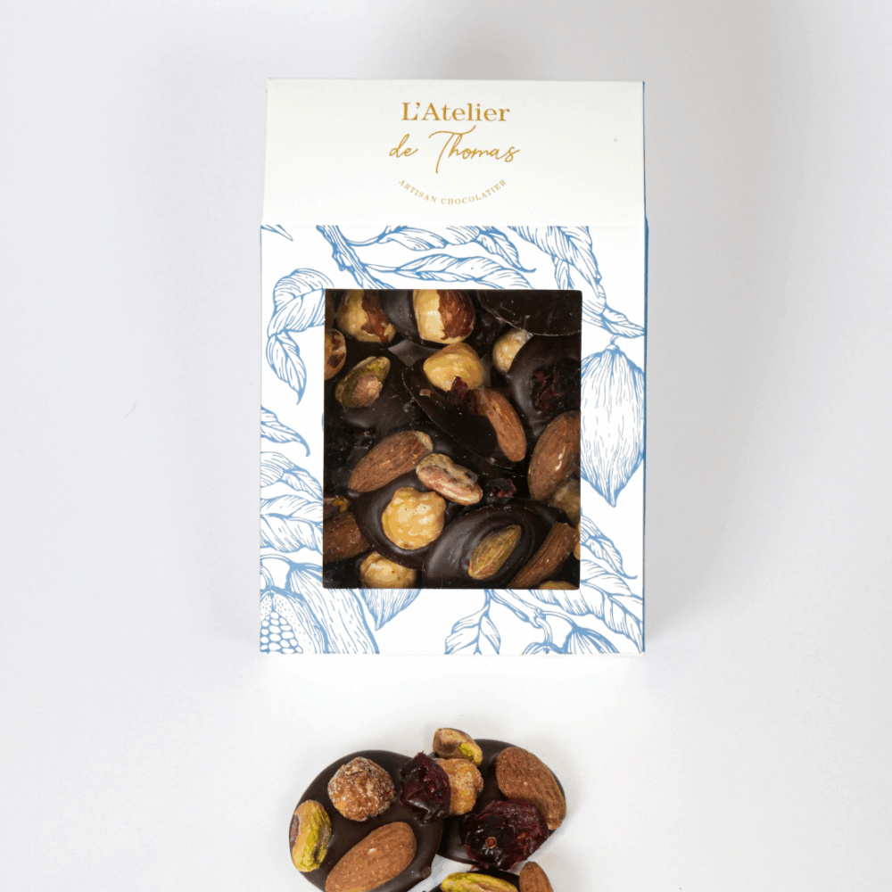 Palets de chocolat noir 66 % et lait 40 %, garnis de noisettes grillées, amandes, pistaches et cranberry, réalisés par L’Atelier de Thomas.